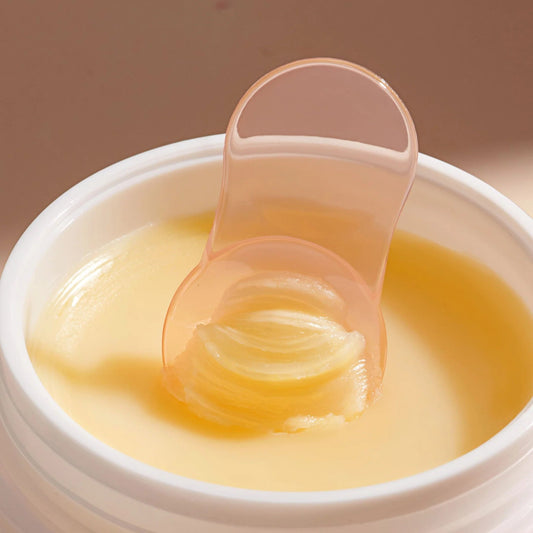 Jar of Wonder Balm Melting Cleanser with a scoop inside, on a beige background