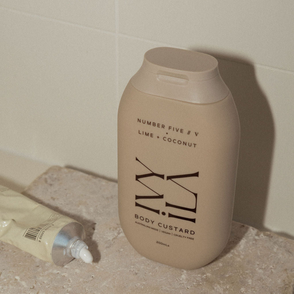 Beige bottle labeled 'Number Five' on a bathroom counter with a tube and ring beside it.