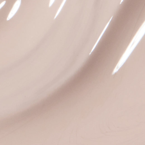 A close-up of a glossy, smooth surface in a very light warm beige or blush tone with soft curved highlights.