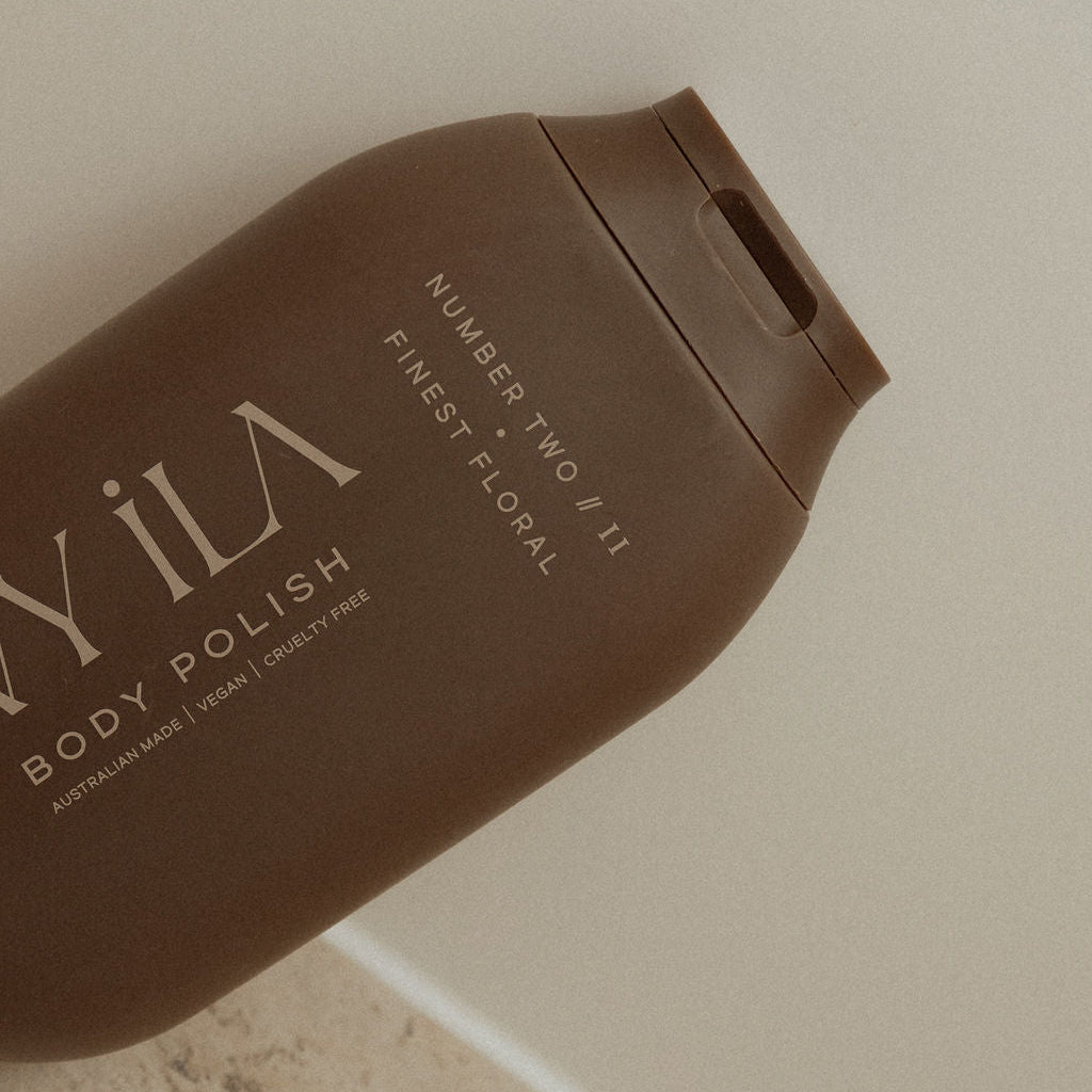Brown bottle of Yila body polish on a neutral background