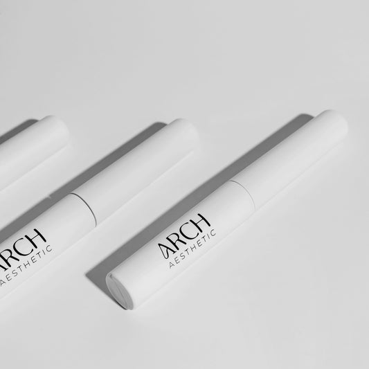 Two white cosmetic tubes with 'ARCH Aesthetics' branding on a light gray background