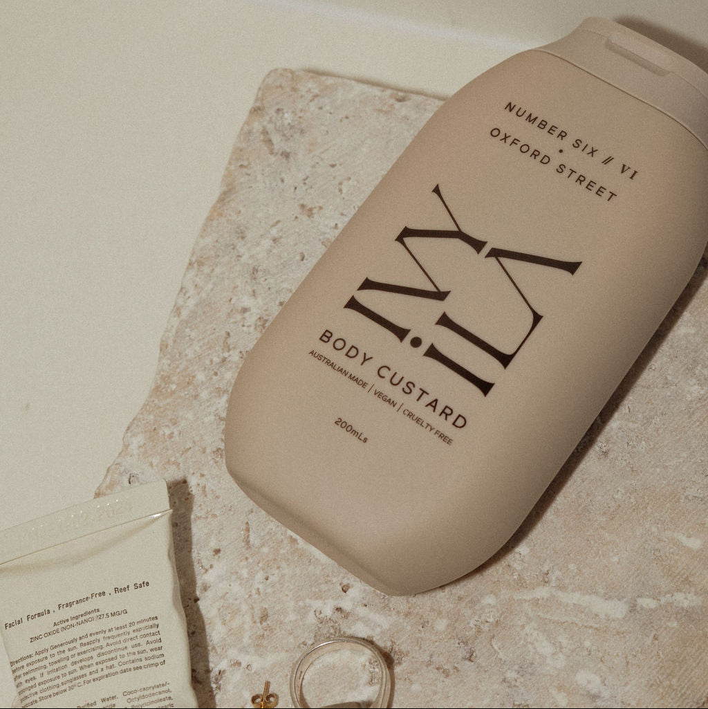 Body custard bottle on a textured surface with a tiled wall background