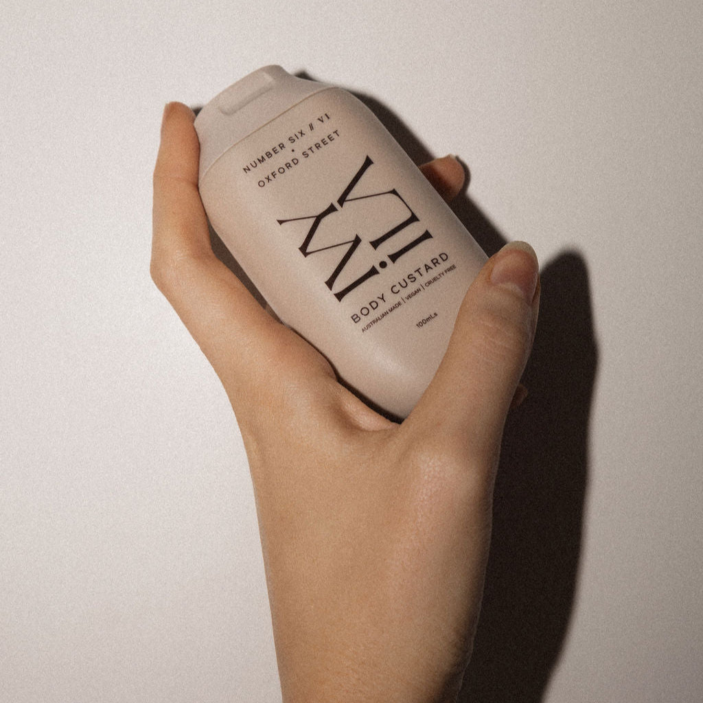 Hand holding a bottle of IVY Beauty product against a plain background