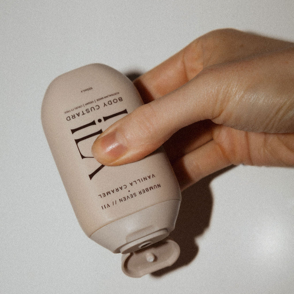 Hand holding a beige bottle with text on a light background