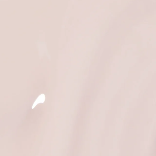A close-up of a smooth, glossy light beige surface with a small white highlight near the lower left.