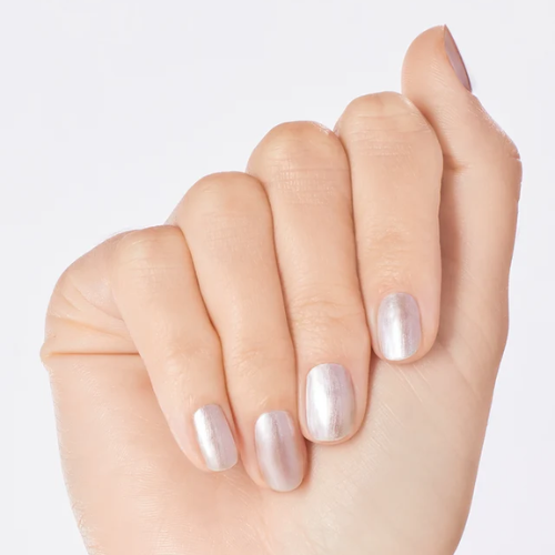 A close-up of a hand with manicured nails painted in a glossy, shimmery pale pink-lilac polish against a clean white background.