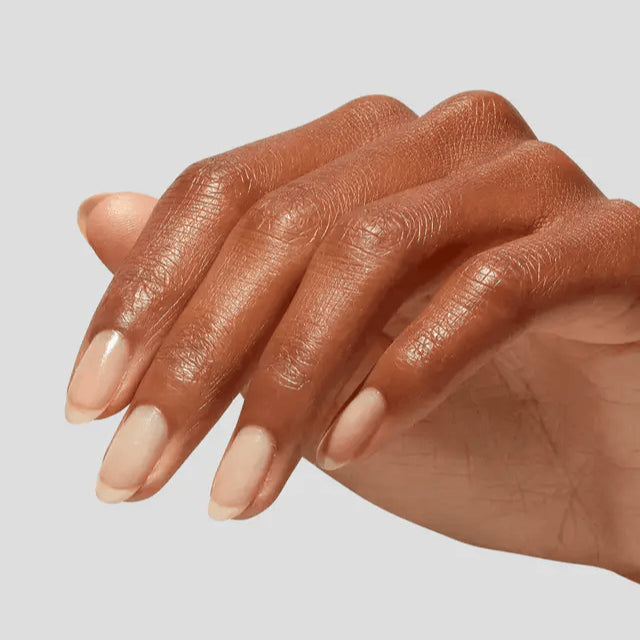 Close-up of a hand with beige nail polish on a light gray background
