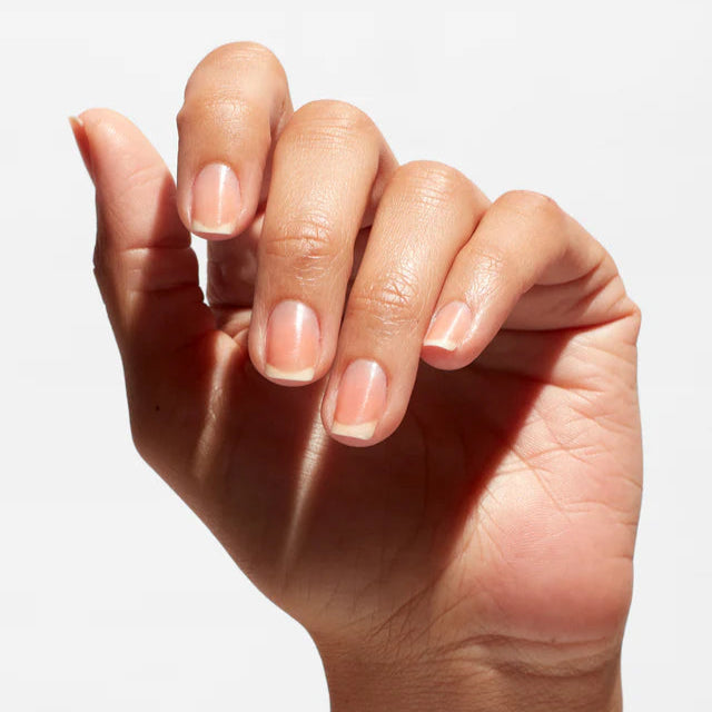 Close-up of a hand with light pink nail polish on a white background