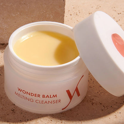 Open jar of Wonder Balm Melting Cleanser on a beige background
