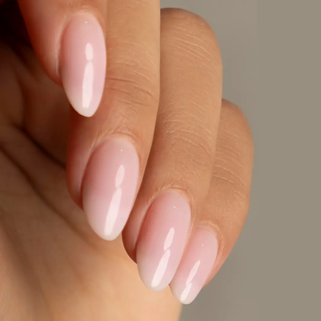 Close-up of a hand with pink nail polish on a neutral background
