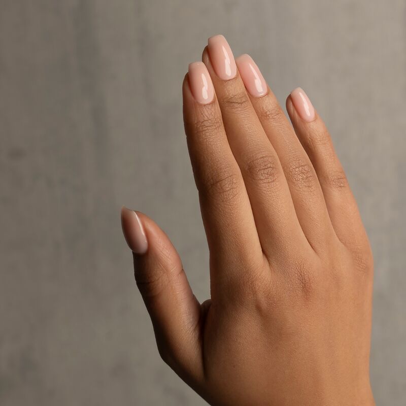 Hand with light pink nail polish on a neutral background