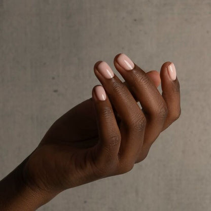 Two hands with light pink nail polish against a neutral background