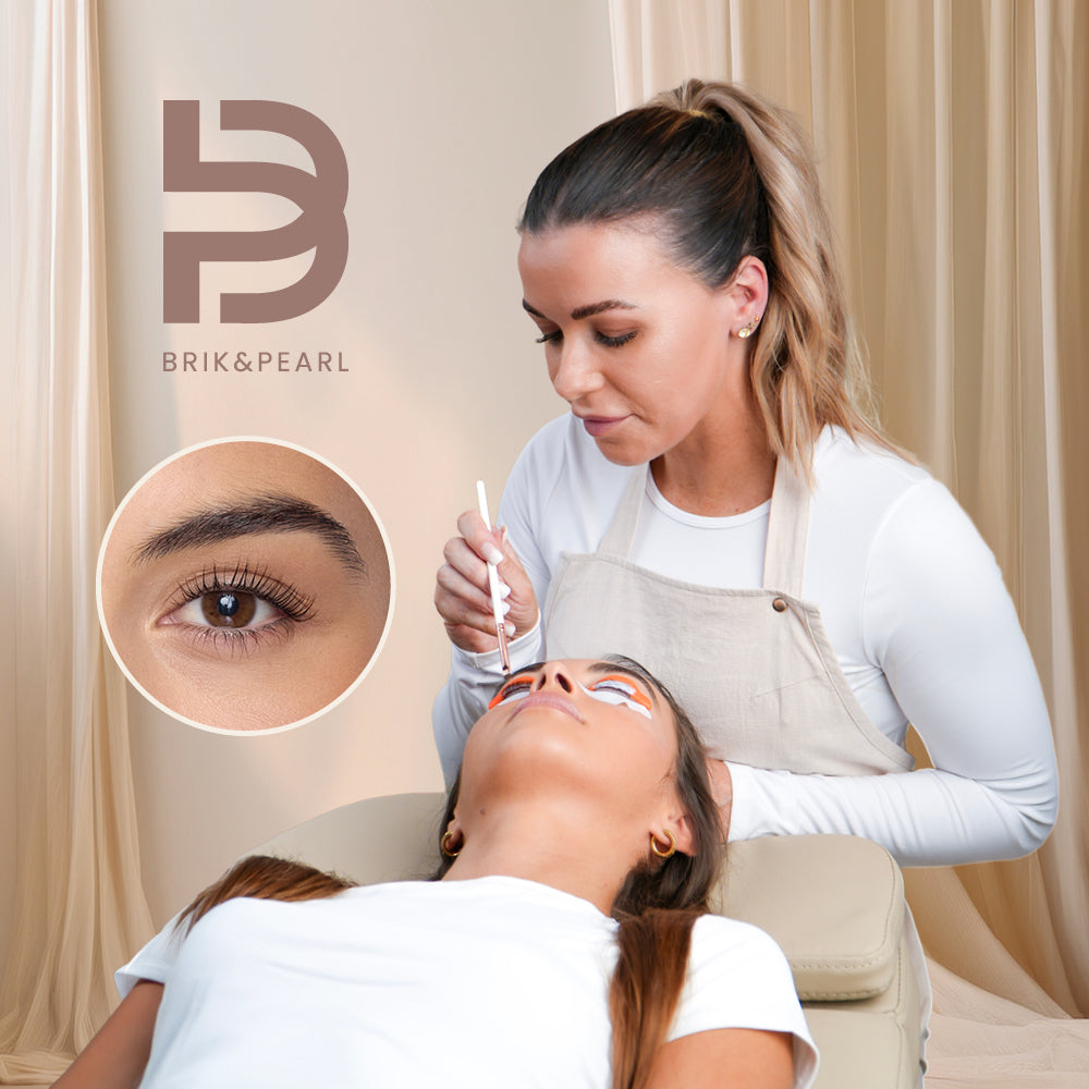 A brow specialist from Brik & Pearl is performing a brow lamination treatment on a client lying down. The specialist holds a white tool over the client's brow, with a circular inset showing a close-up of the treated eyebrow.