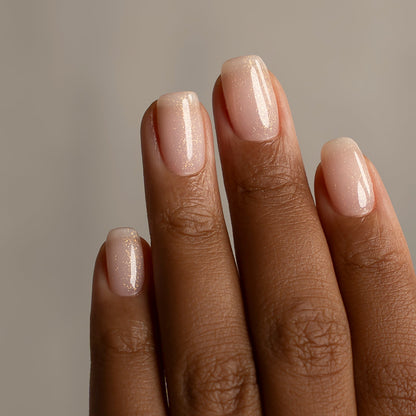 Close-up of a hand with beige nail polish on a neutral background
