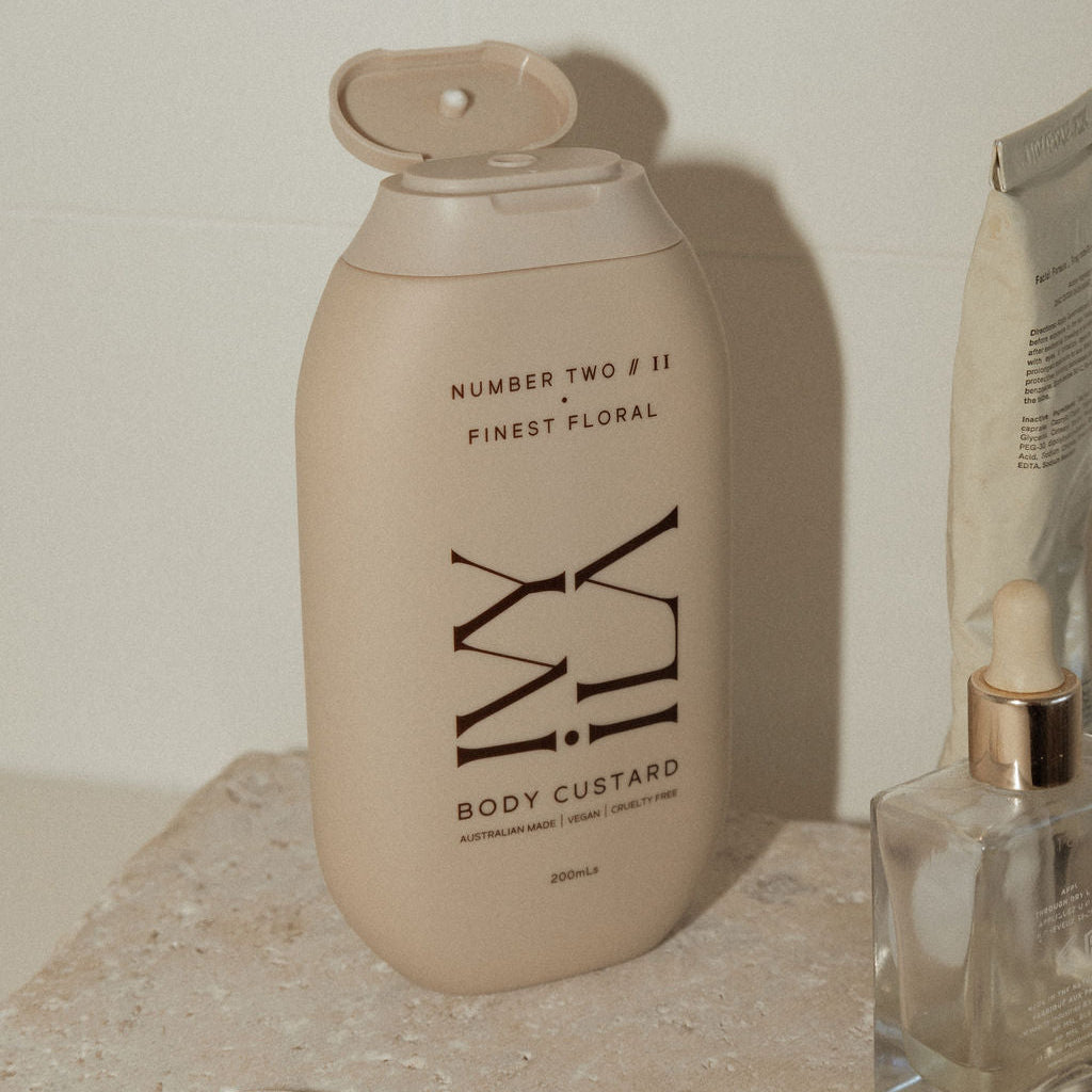 Body custard bottle labeled 'Number Two' on a surface with jewelry and another product.