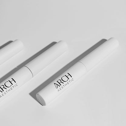 Two white cosmetic tubes with 'ARCH Aesthetics' branding on a light gray background