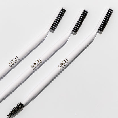 Three white eyebrow brushes with black bristles on a light gray background, branded 'ARCH'.
