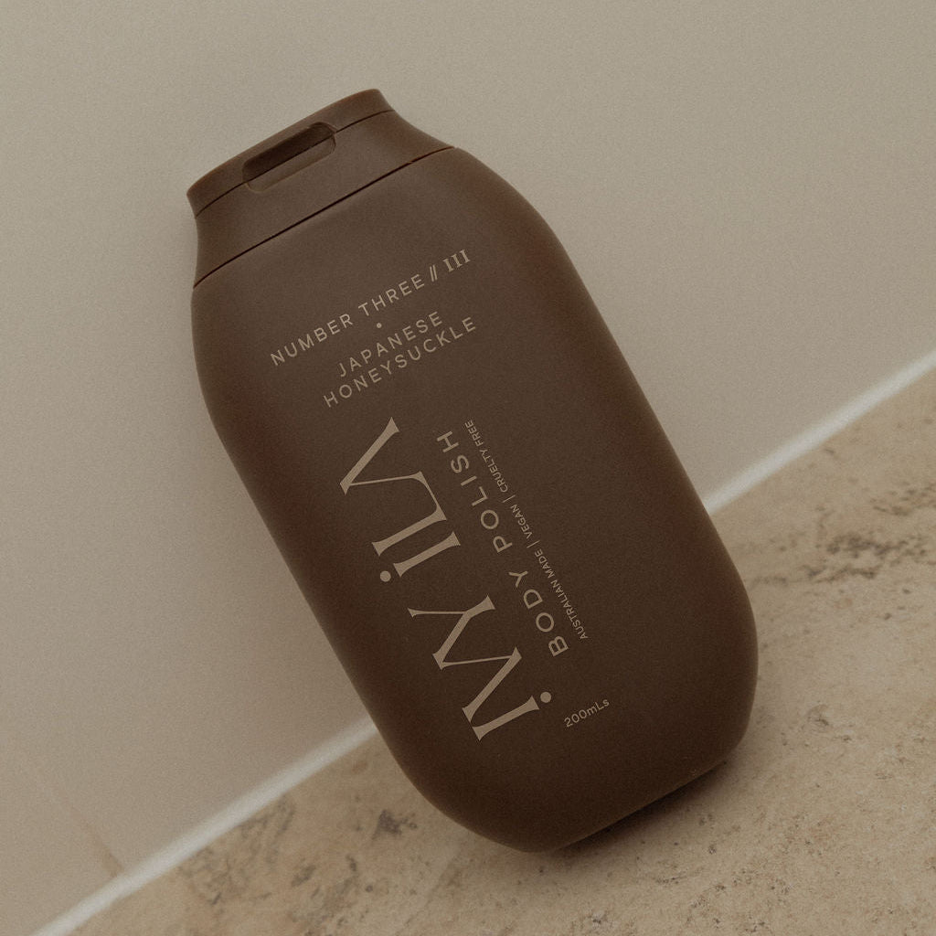 Brown bottle of IWILY body polish on a beige surface
