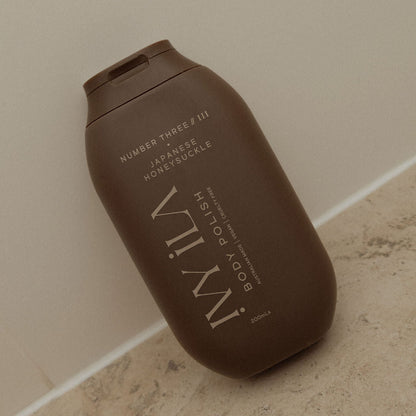 Brown bottle of IWILY body polish on a beige surface