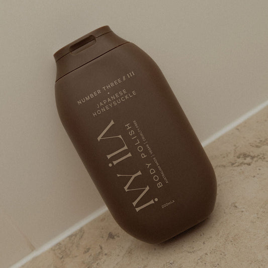 Brown bottle of IWILY body polish on a beige surface