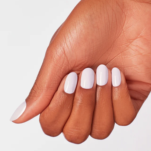 A close-up of a hand with a manicure featuring a glossy, solid pale lavender nail polish on a clean white background.