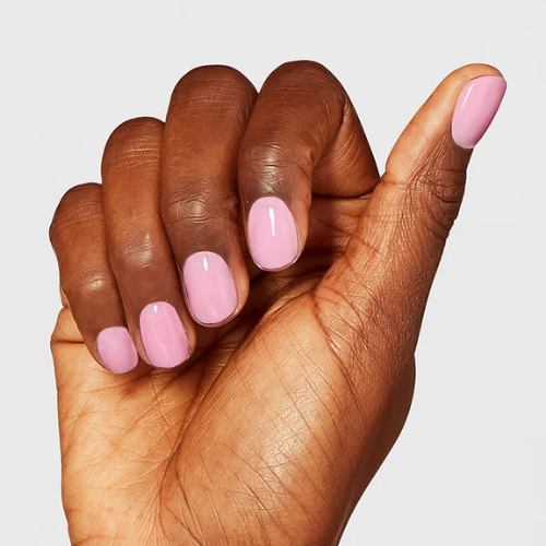 Hand with pink nail polish on a plain background