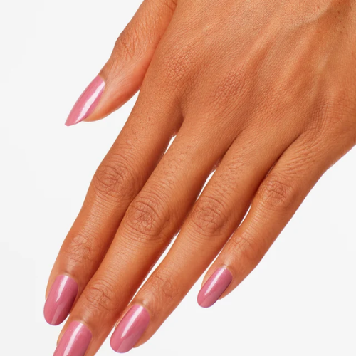 A close-up of a hand with manicured nails painted in a glossy, dusty pink color, set against a clean white background.