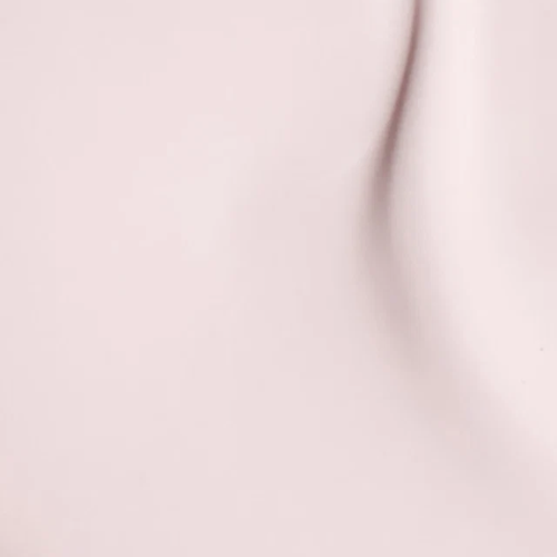 A close-up of a smooth, pale blush pink surface with soft shadows and a subtle curved highlight.